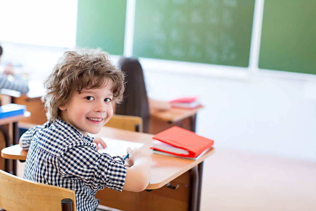 Petit garçon souriant à l'école après son déménagement