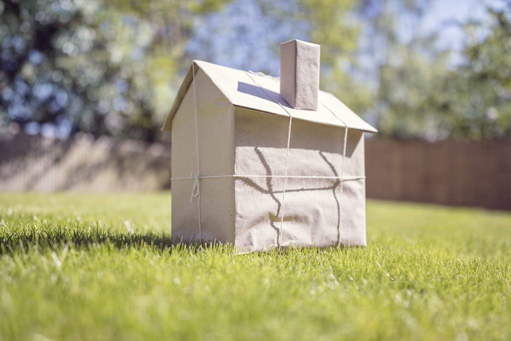 Petite maison en carton posée dans l'herbe