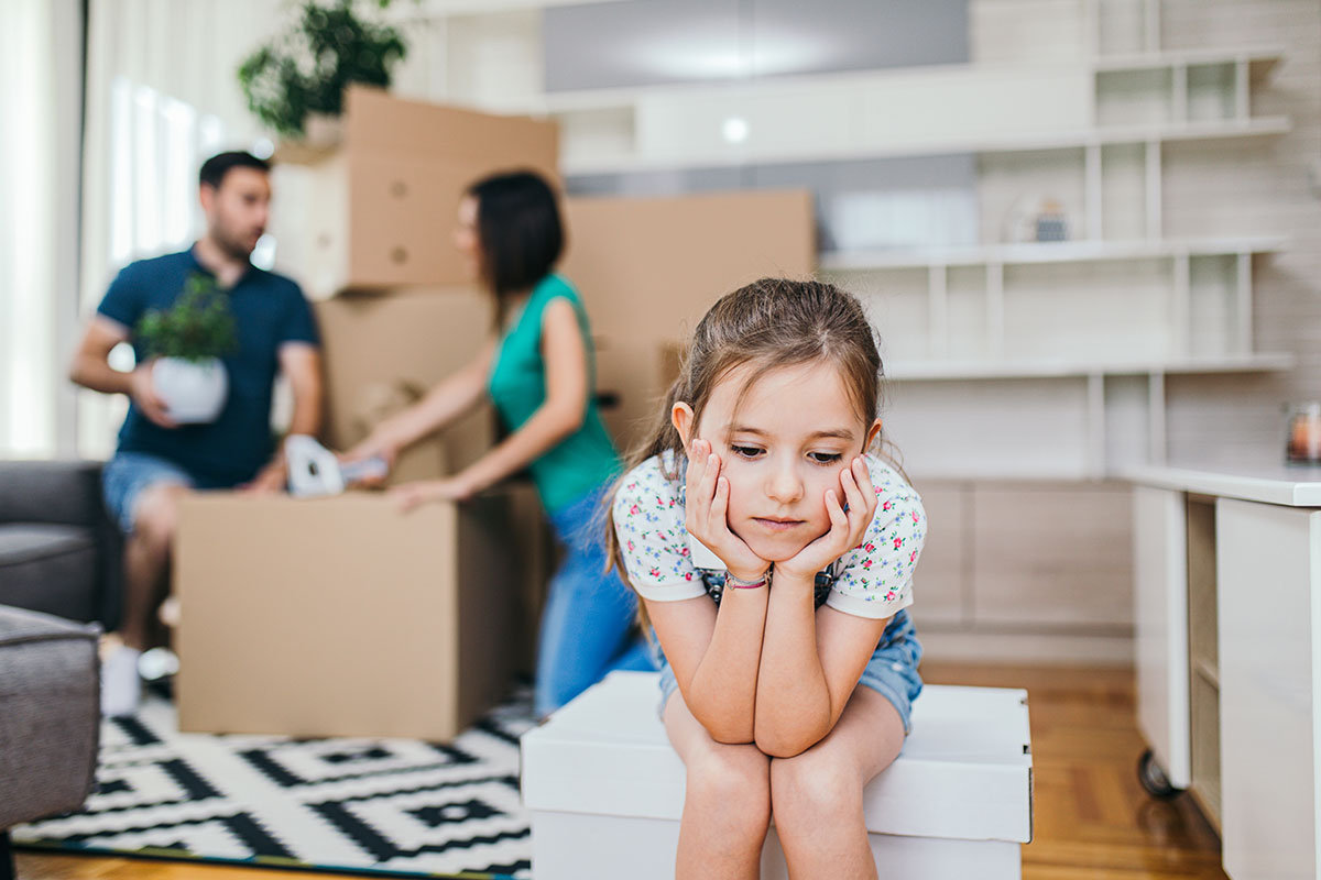 Petite fille assise sur un carton de déménagement